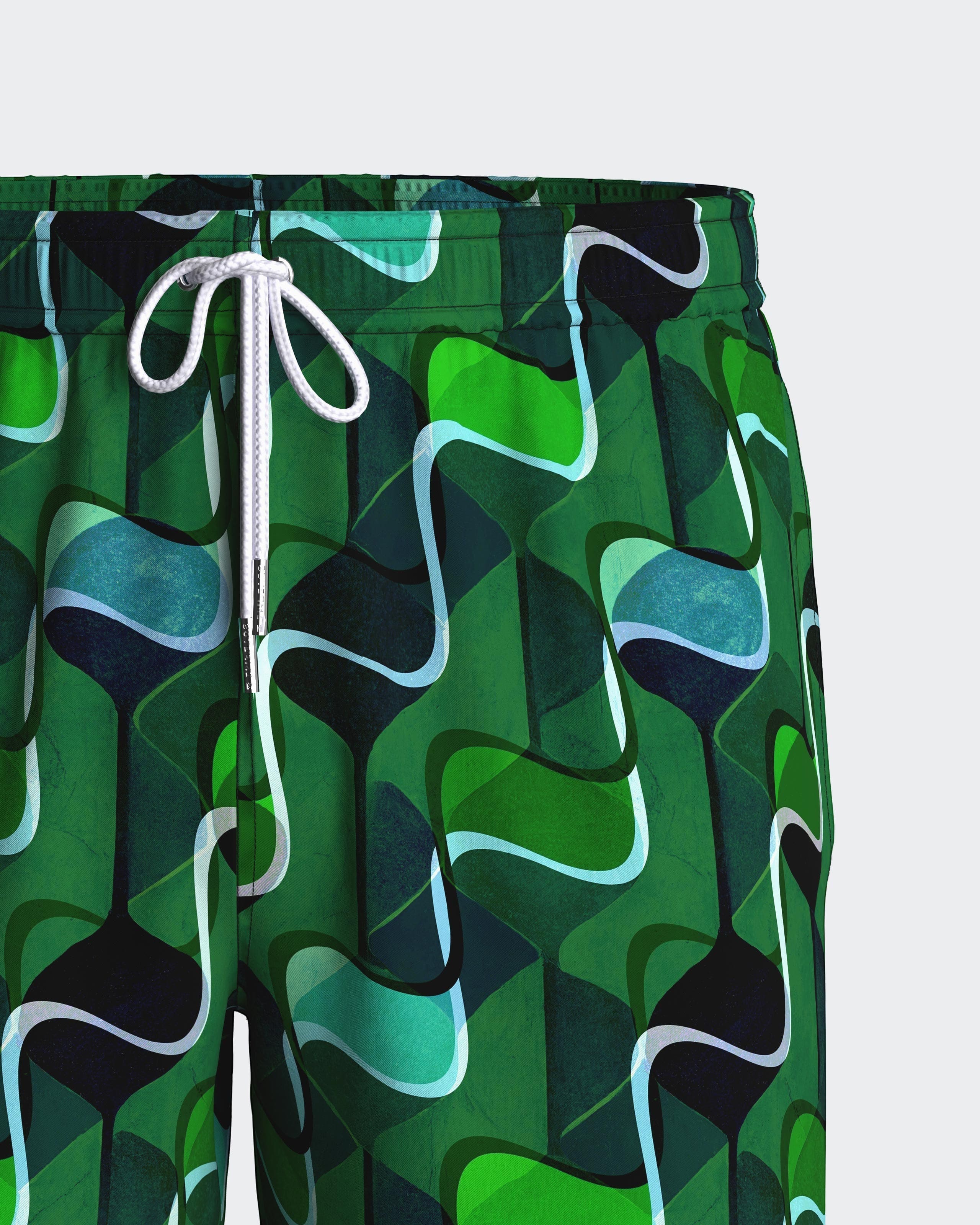 Maison Sarava men's green abstract pattern swim trunks with white drawstring and metal tips.