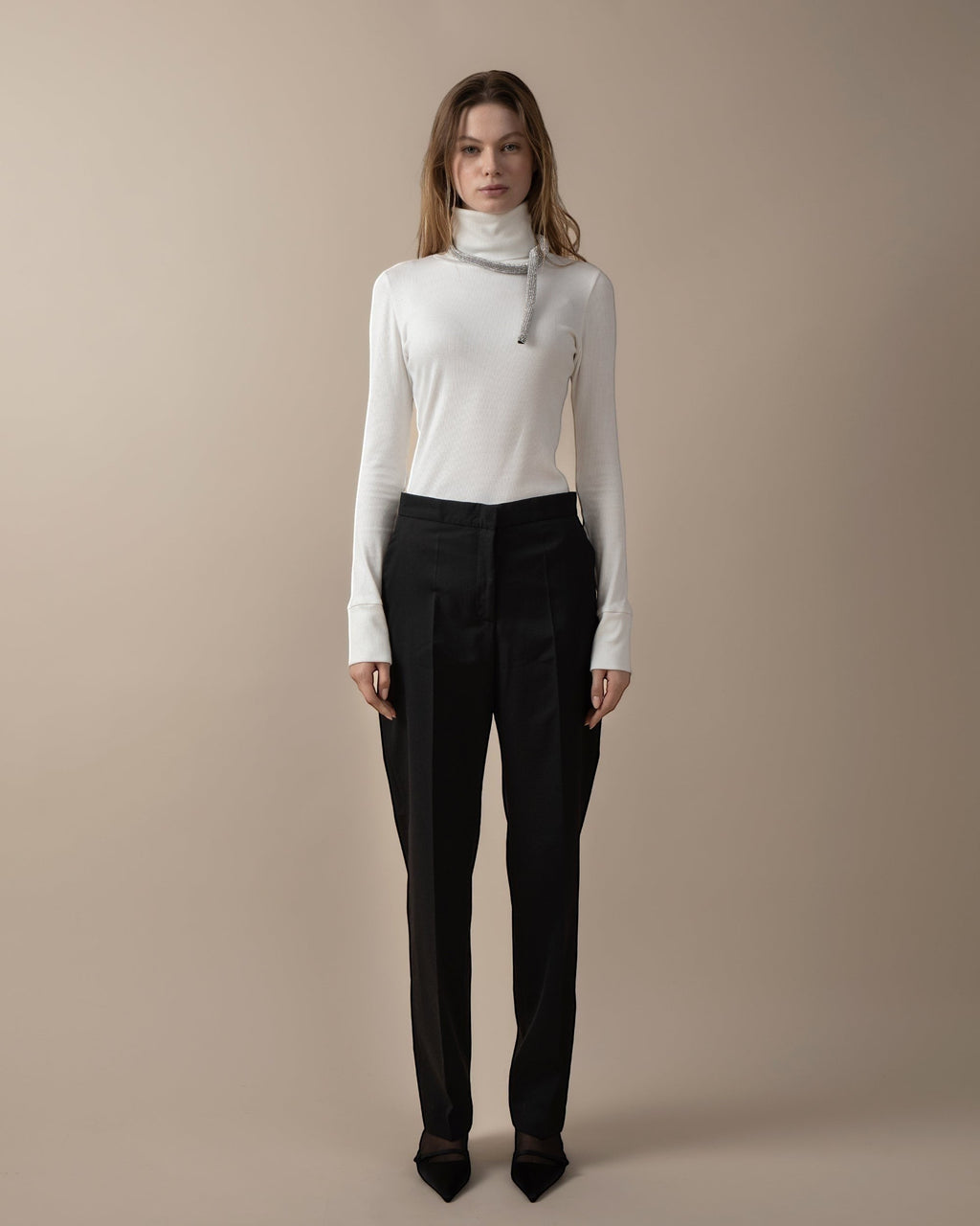 Maison Sarava women's black high-waist trousers with straight fit, two front patch pockets, and A-design stitching on back pockets. Cut detail below the knee.