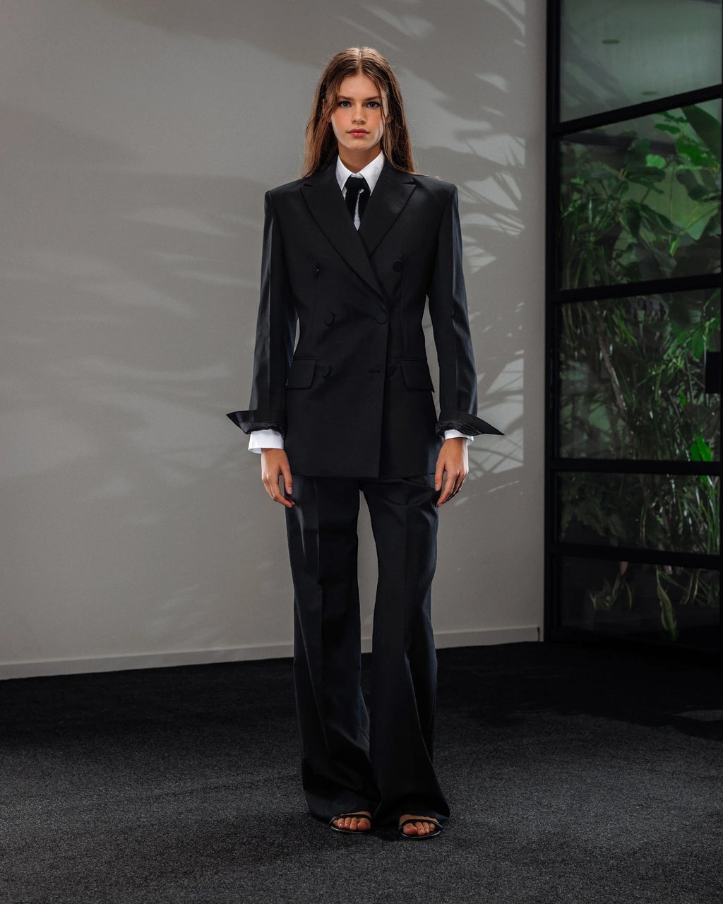 Maison Sarava women's black wool double-breasted blazer with peak lapels and fitted cut, paired with matching trousers.