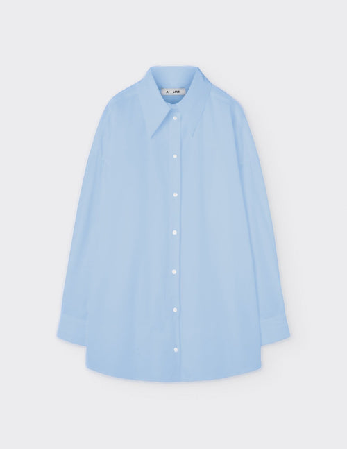 Maison Sarava light blue oversized cotton shirt with pointed collar, dropped shoulders, and double-pleat cuffs.