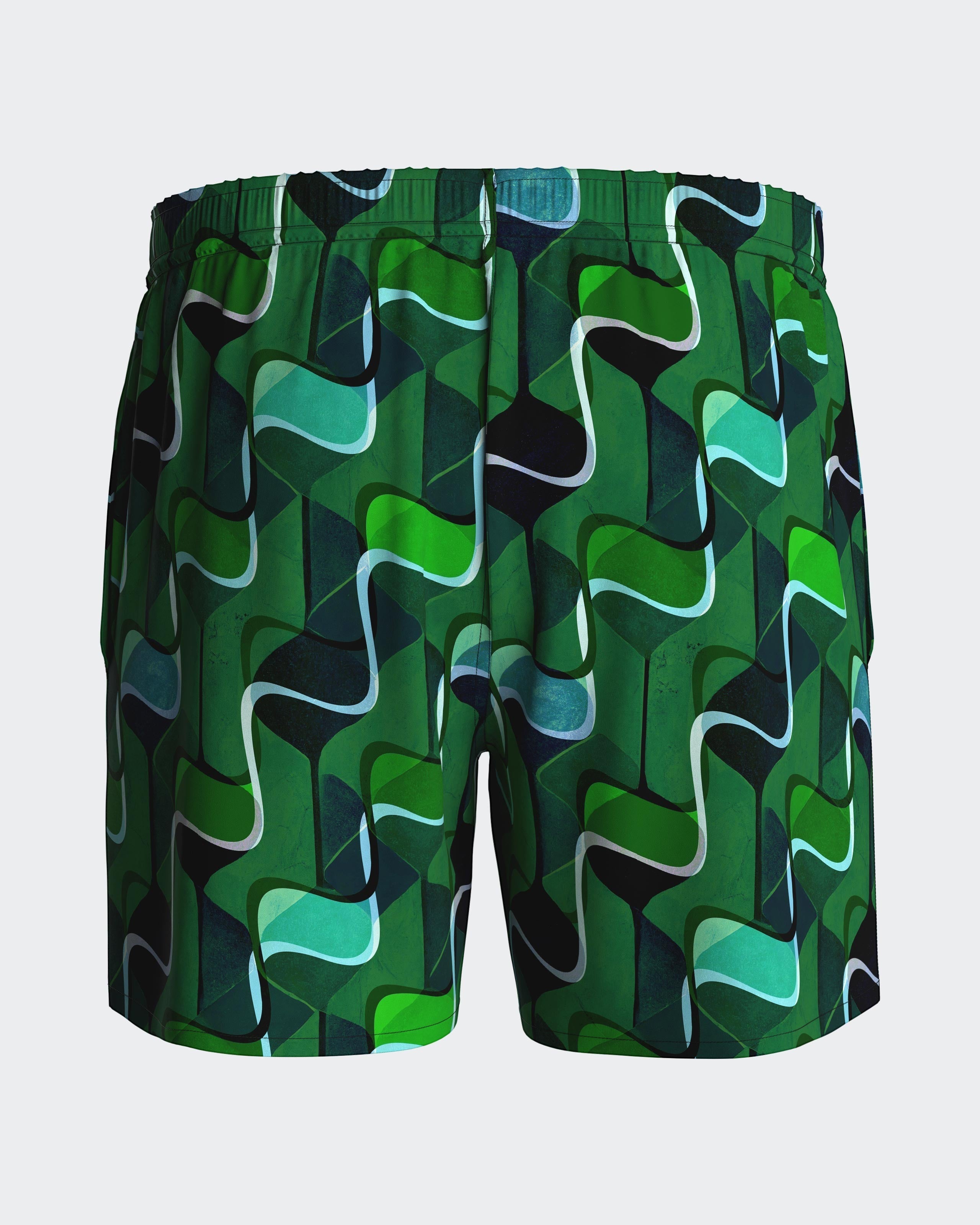Maison Sarava men's green abstract pattern swim trunks with elastic waistband and side slits.
