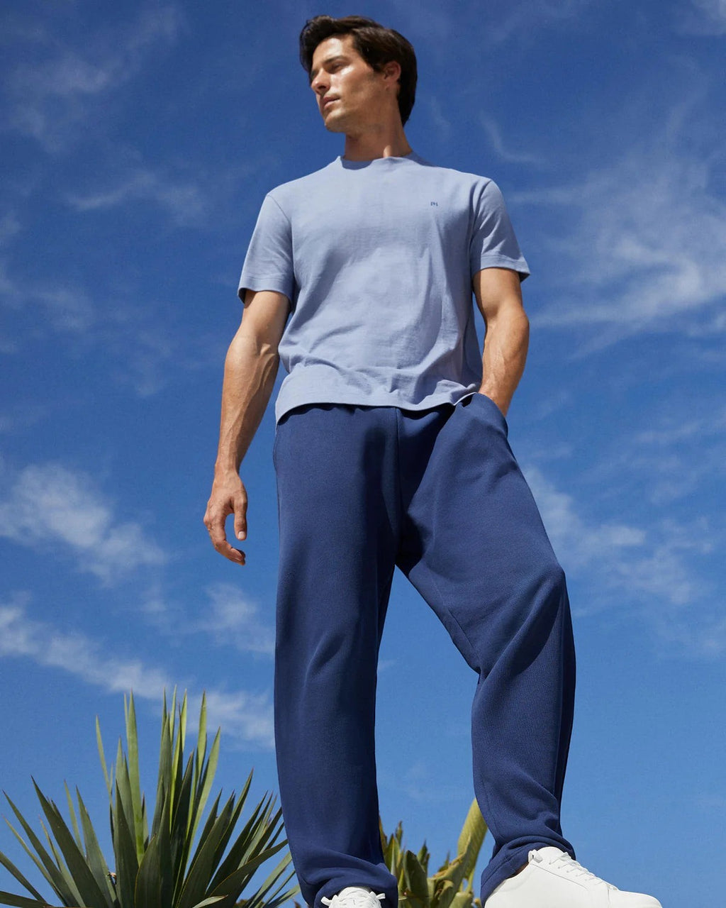 Maison Sarava light blue cotton t-shirt with subtle chest embroidery and round neckline, worn by a man outdoors.