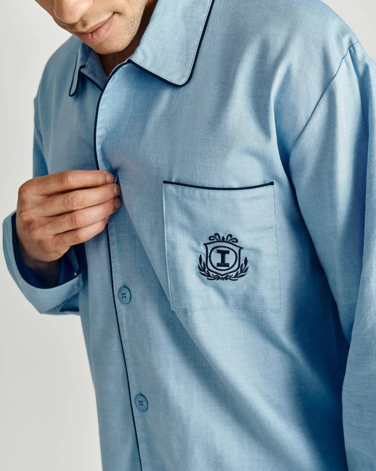 Maison Sarava light blue cotton pajama set with black piping and embroidered crest on pocket. Button-down shirt.