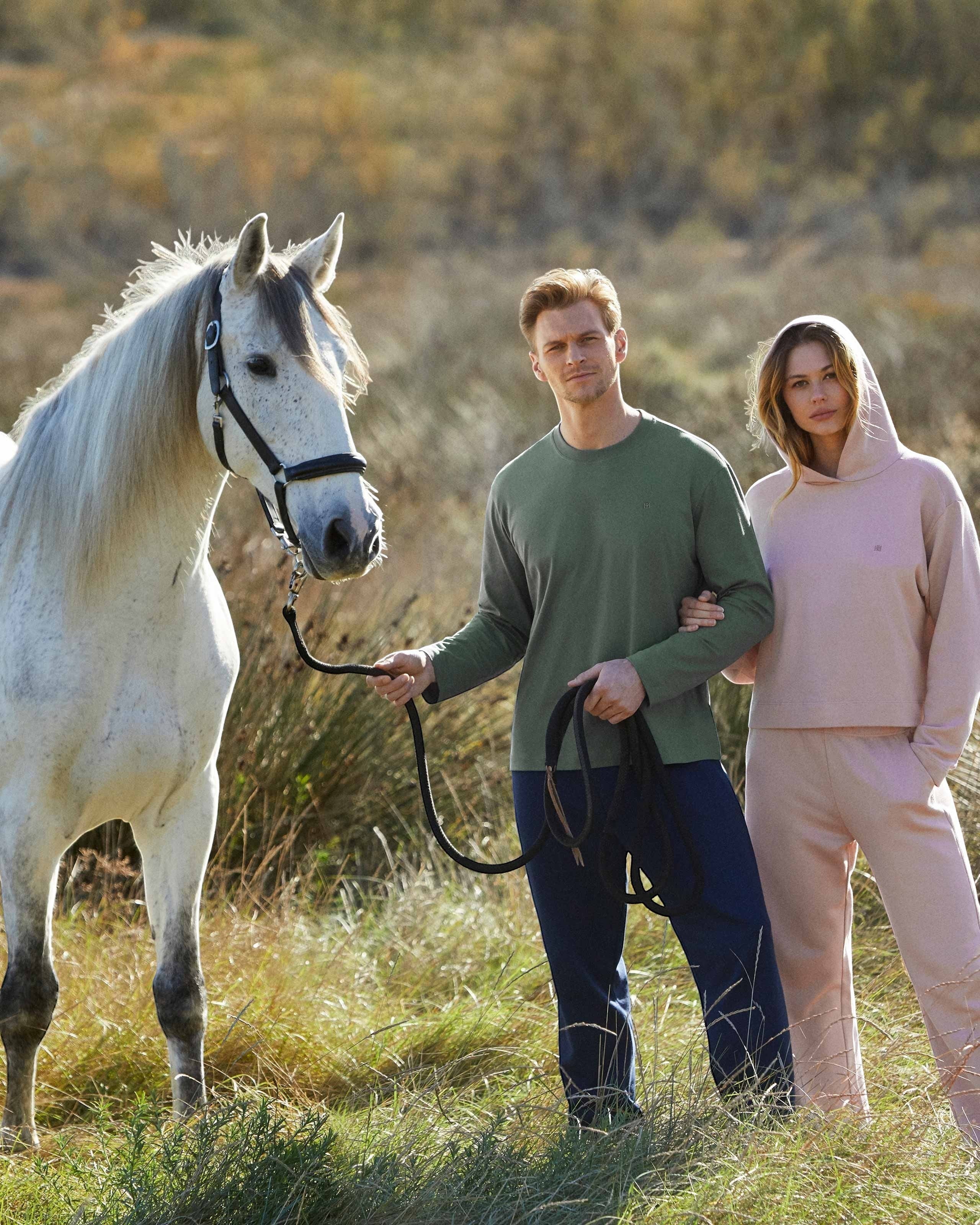 Maison Sarava couple in comfortable lounge pants and hoodie outdoors with a horse