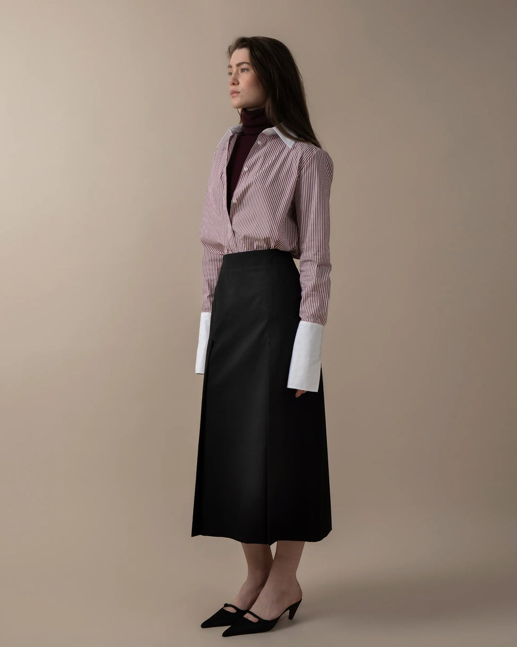 Maison Sarava women's red and white striped fitted shirt with white collar and cuffs, worn over a burgundy turtleneck and black midi skirt.