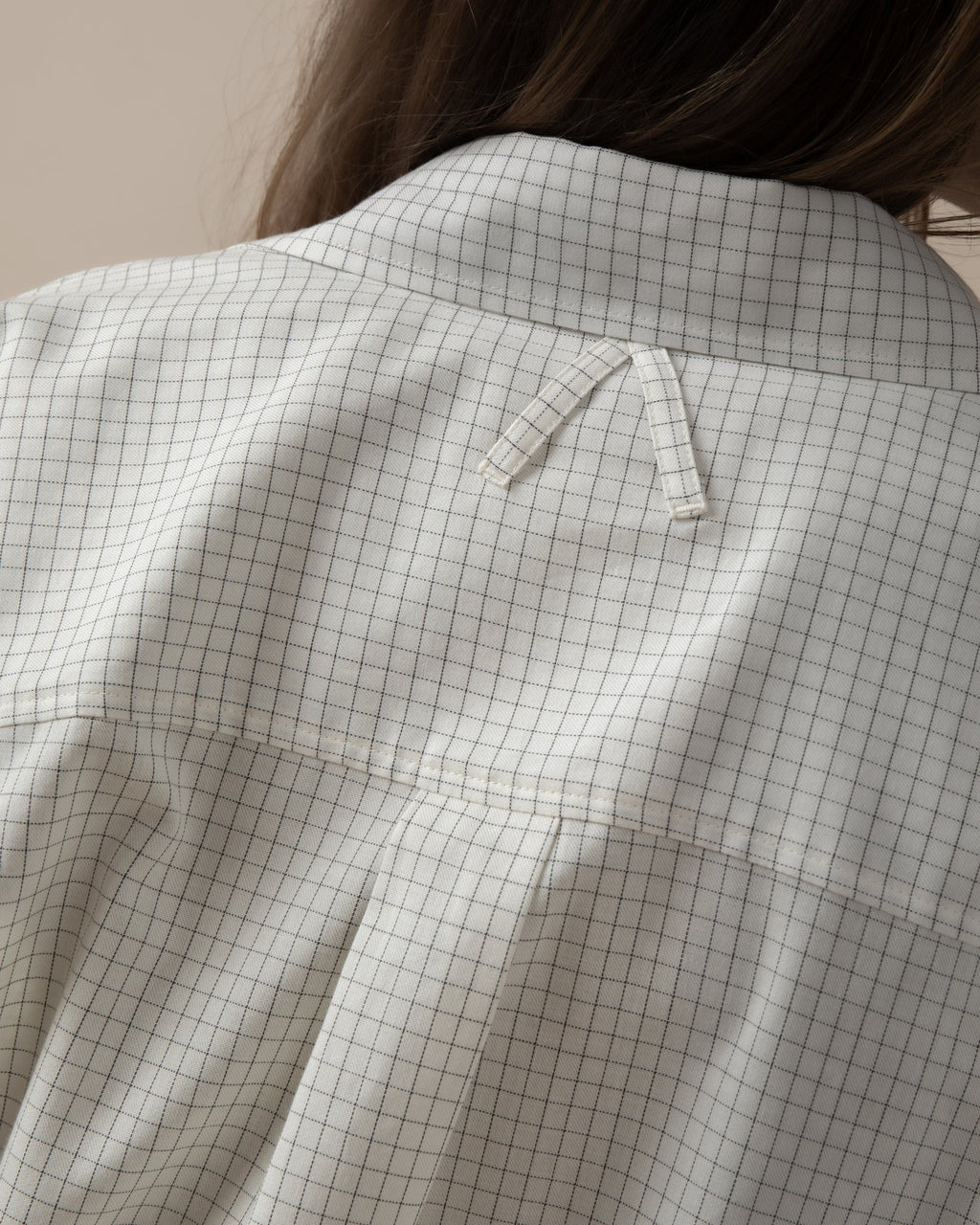 Maison Sarava women's white oversized shirt with black grid pattern, pointed collar, and unique A-design back loop detail.