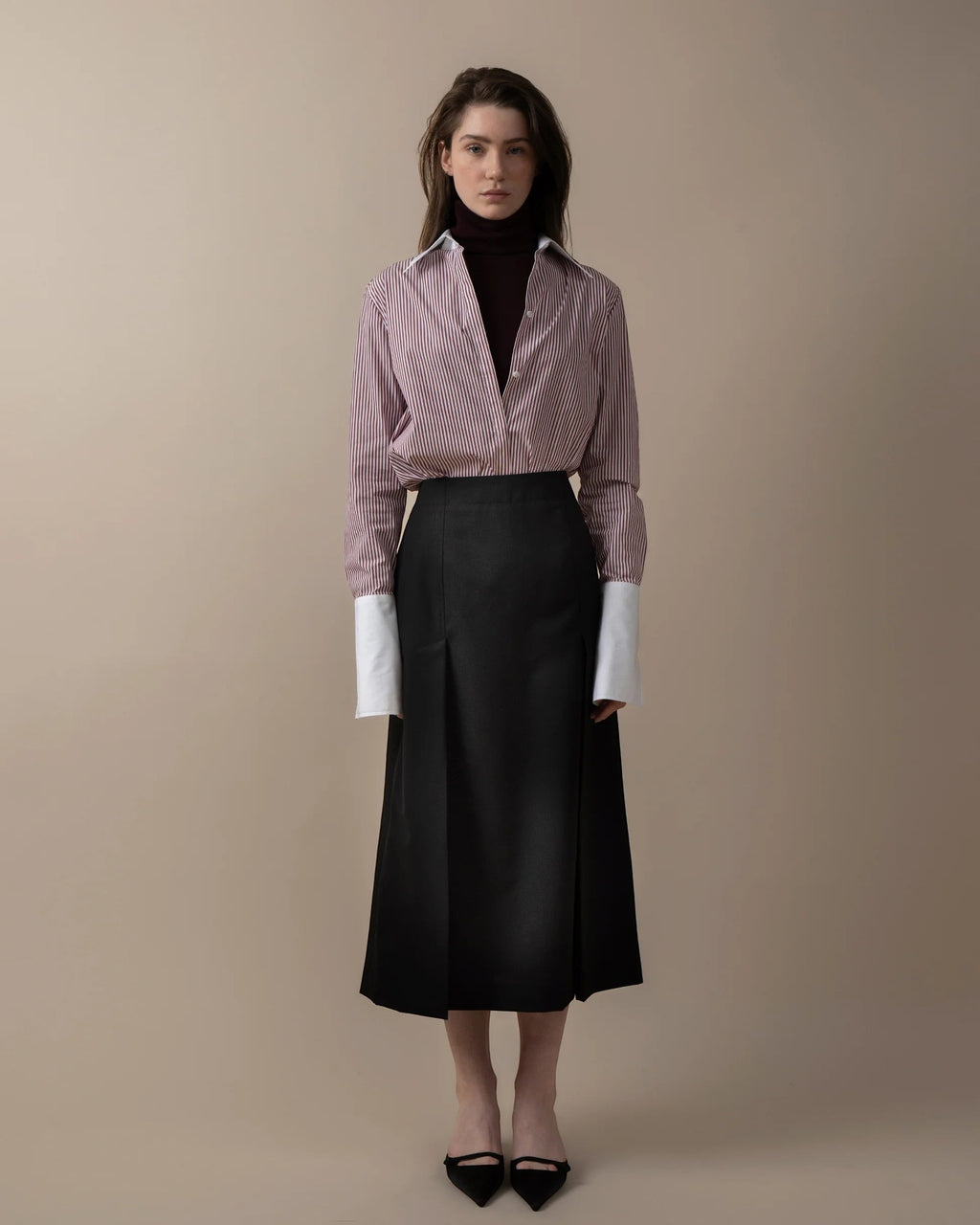 Maison Sarava women's fitted red and white striped shirt with white cuffs, worn over a dark turtleneck and black skirt.